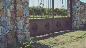 A gated entrance with stone walls and a metal gate featuring decorative patterns.