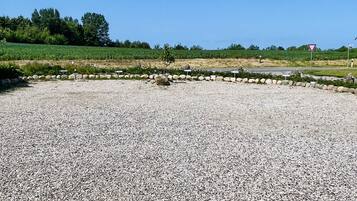 A gravel parking area with a stone wall and a field in the background.