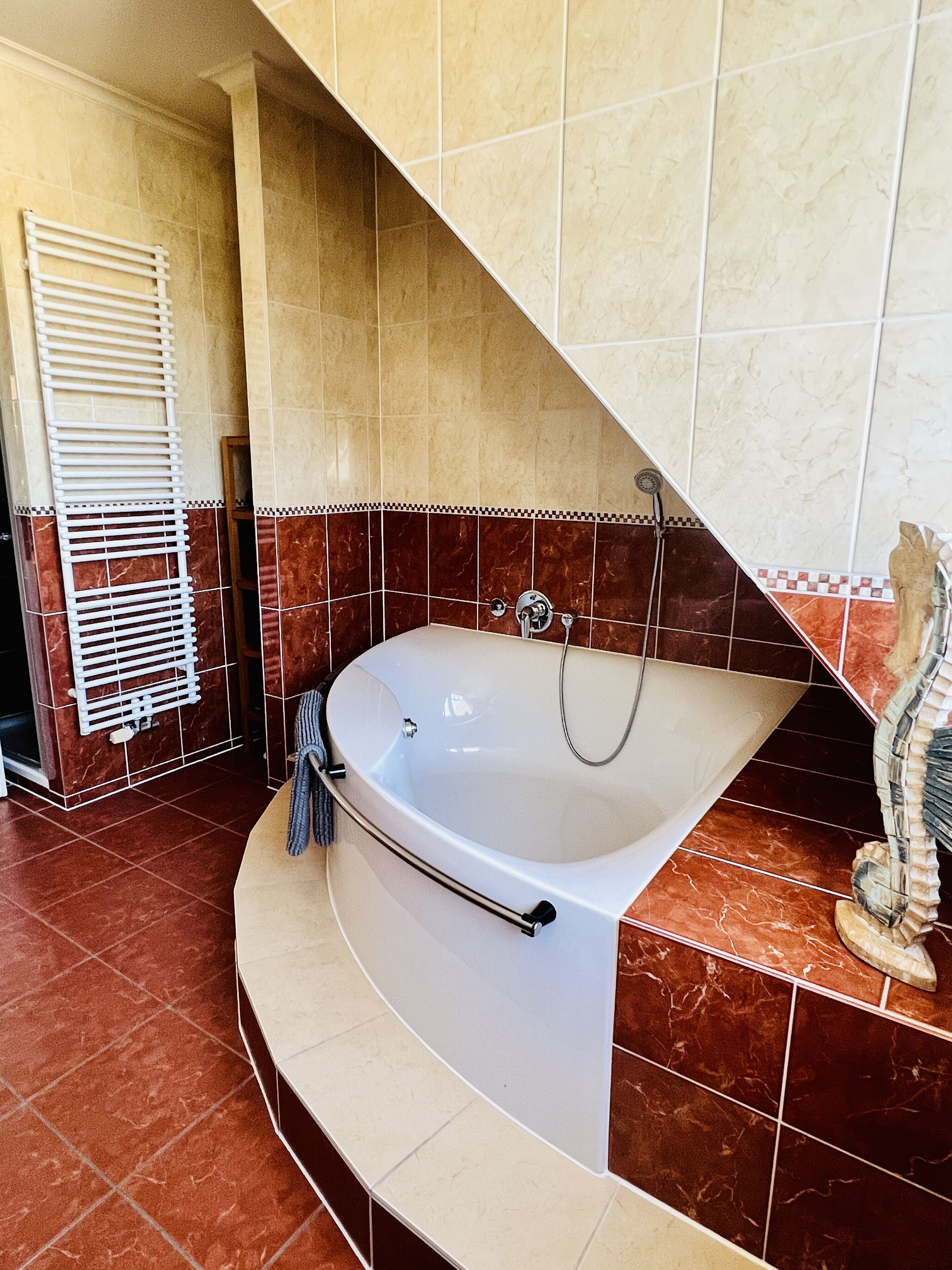Een moderne badkamer met een vrijstaand bad, een handdoekhouder en een douchekop.