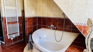 A modern bathroom with a freestanding bathtub, a towel rack, and a showerhead.