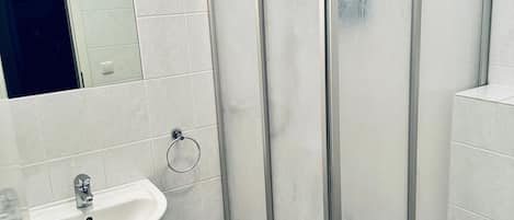 Une salle de bain équipée d’une douche, d’un lavabo et de toilettes.