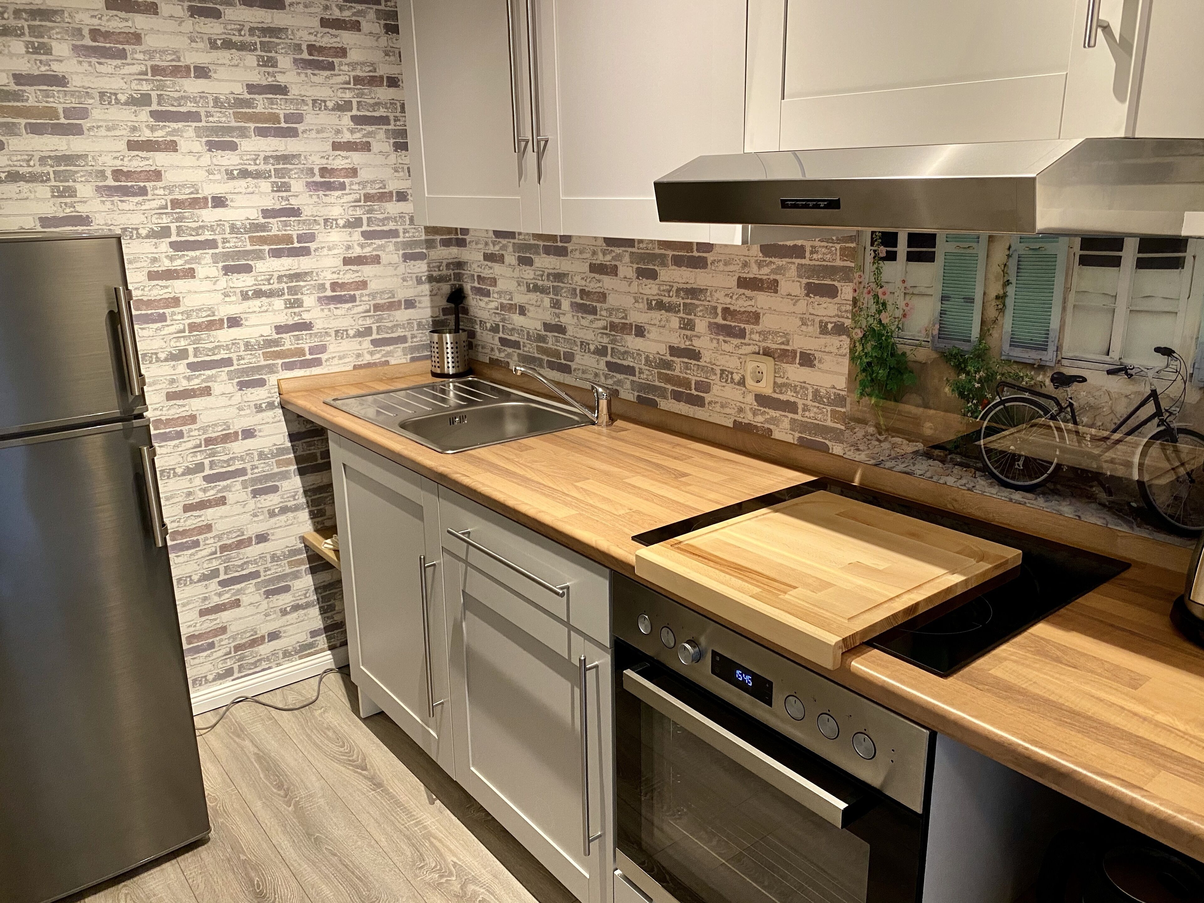 Una cocina moderna con protector mural de ladrillo, electrodomésticos de acero inoxidable y encimera de madera.