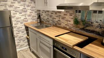 Una cocina moderna con protector mural de ladrillo, electrodomésticos de acero inoxidable y encimera de madera.