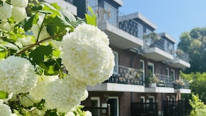 A modern building with multiple balconies and a garden with white flowers. - Haus Stern (Wangels)