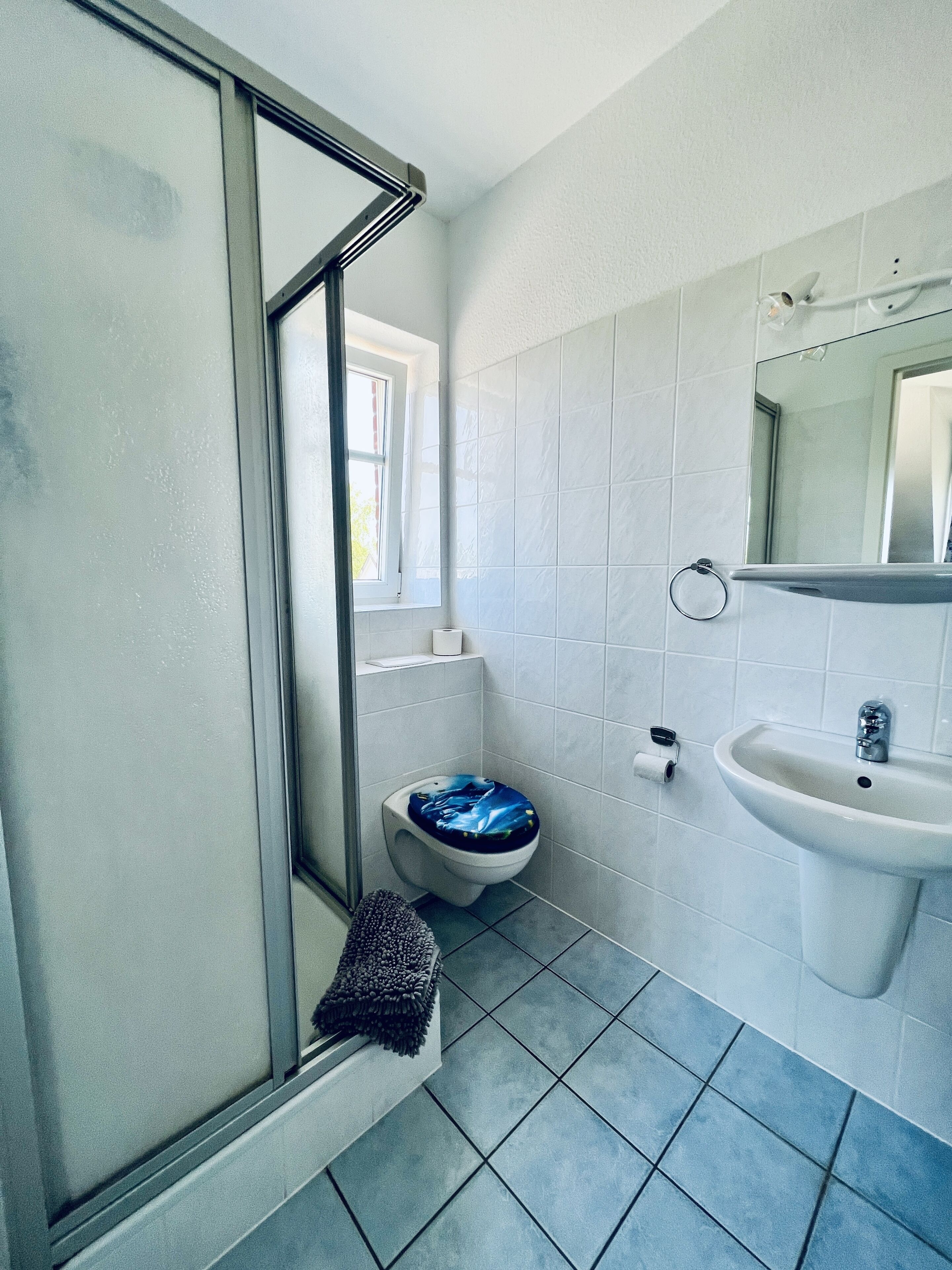 A bathroom with a toilet, sink, and a shower area.