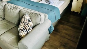 A bedroom with a bed, a nightstand, a wardrobe, a sofa, and a view of the beach. - Haus Stern (Wangels)