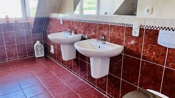 Une salle de bain avec deux lavabos, des toilettes et un miroir.