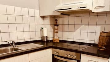 Una cocina con armarios blancos, un lavamanos de acero inoxidable y una encimera negra.