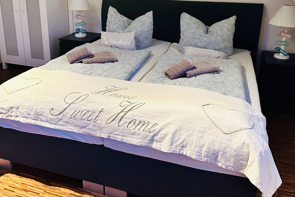 A bedroom with a bed, two nightstands, a wardrobe, and decorative wall art.