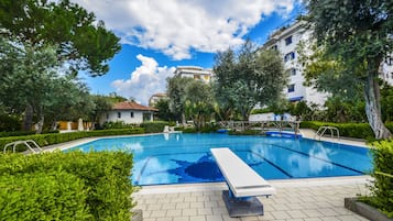 Una piscina al aire libre de temporada, tumbonas