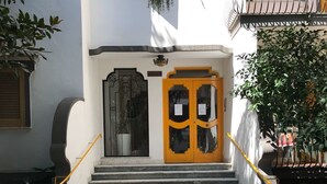Degraus de concreto levam a um edifício com uma porta amarela e um painel decorativo preto acima dela.