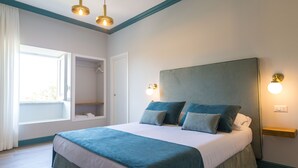 Quarto com cama grande, duas luminárias de cabeceira, janela com vista e armário embutido.