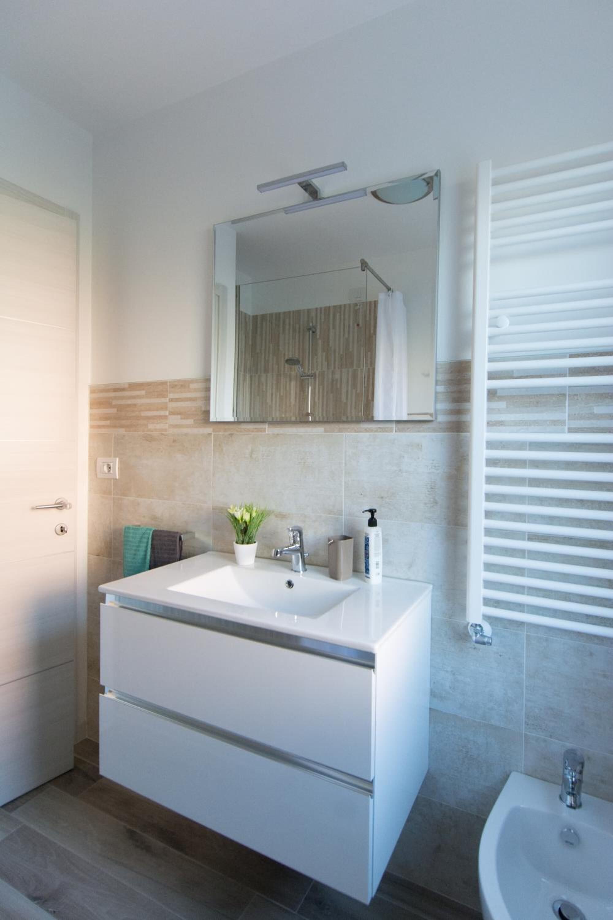 A modern bathroom with two sinks, a mirror, and a shower.