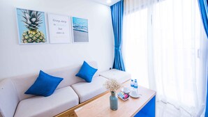 A modern hotel room with a sofa, a coffee table, and artwork on the wall.