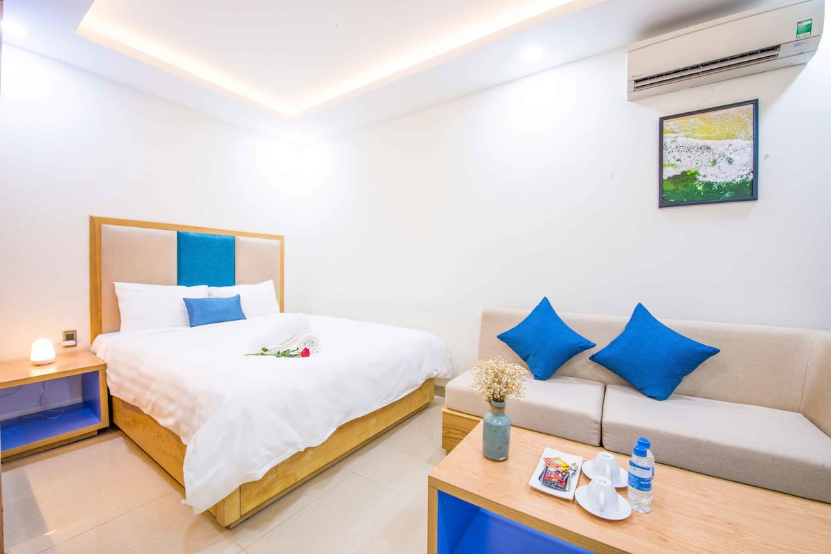 Une chambre d’hôtel équipée d’un lit, d’un canapé, d’une table de chevet, d’une table et d’un appareil de climatisation.