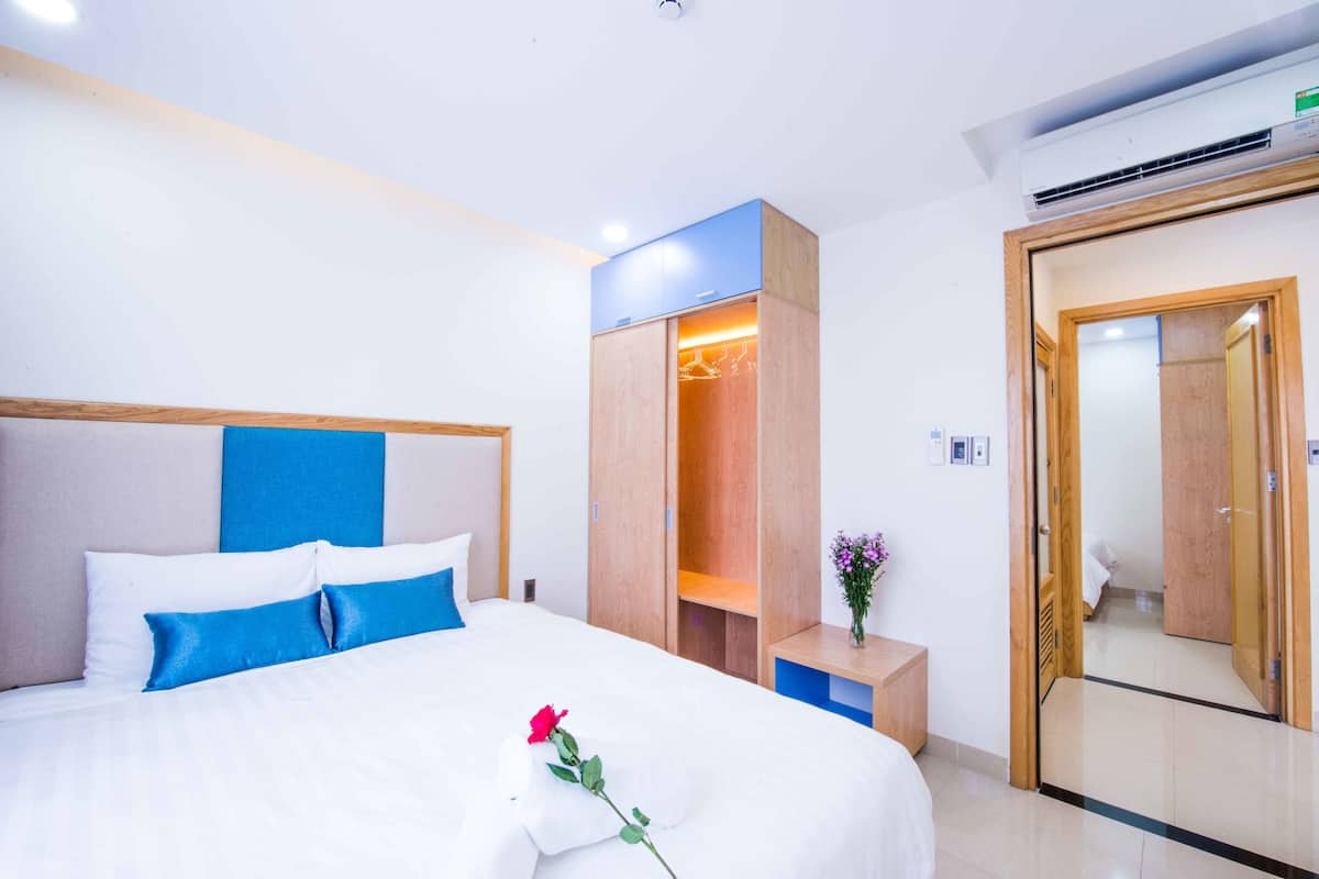 Une chambre d’hôtel avec un lit, une armoire, un miroir et une petite table sur laquelle se trouve un vase.