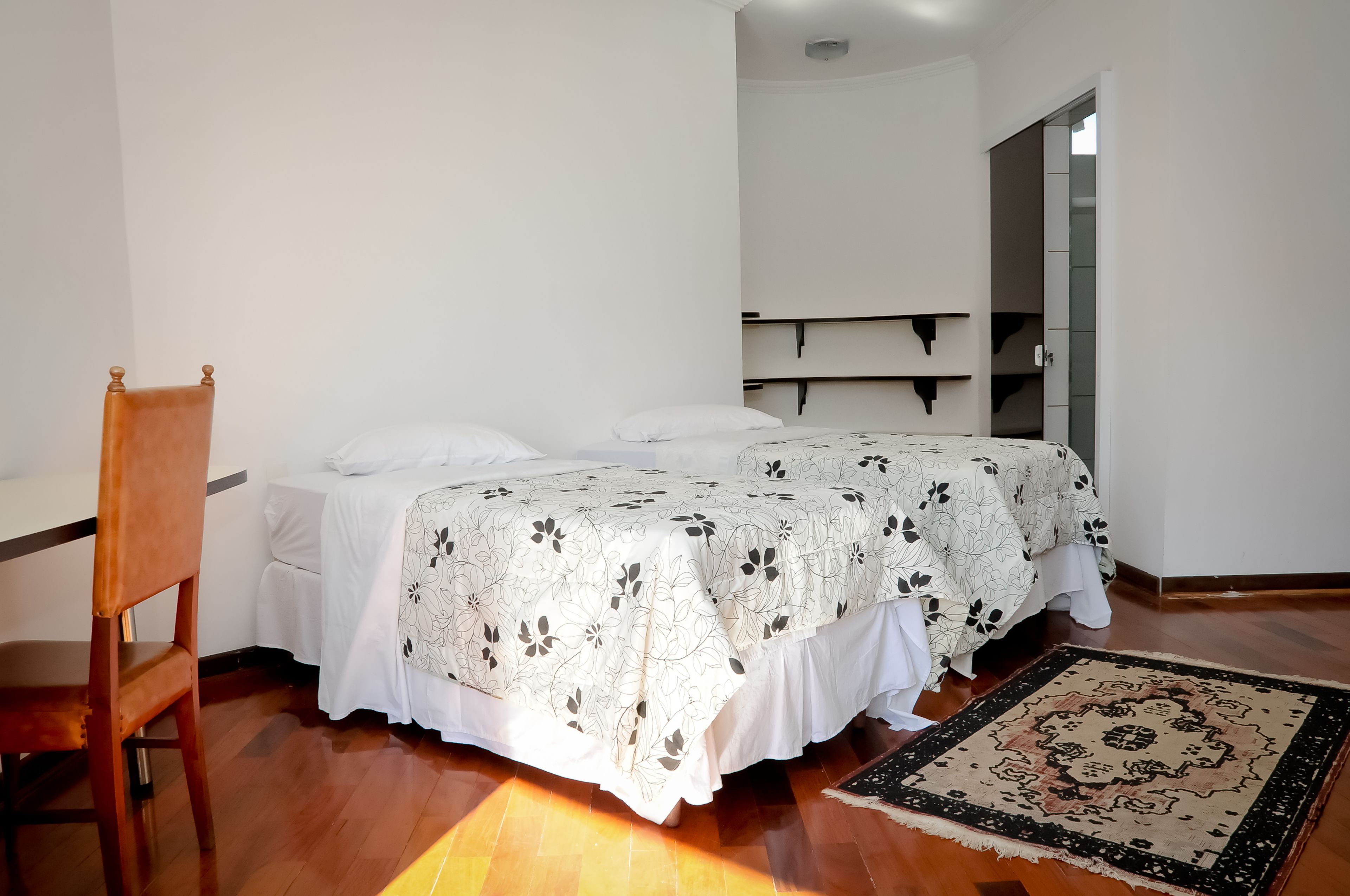 A bedroom with a bed, a chair, a small table, and a rug.