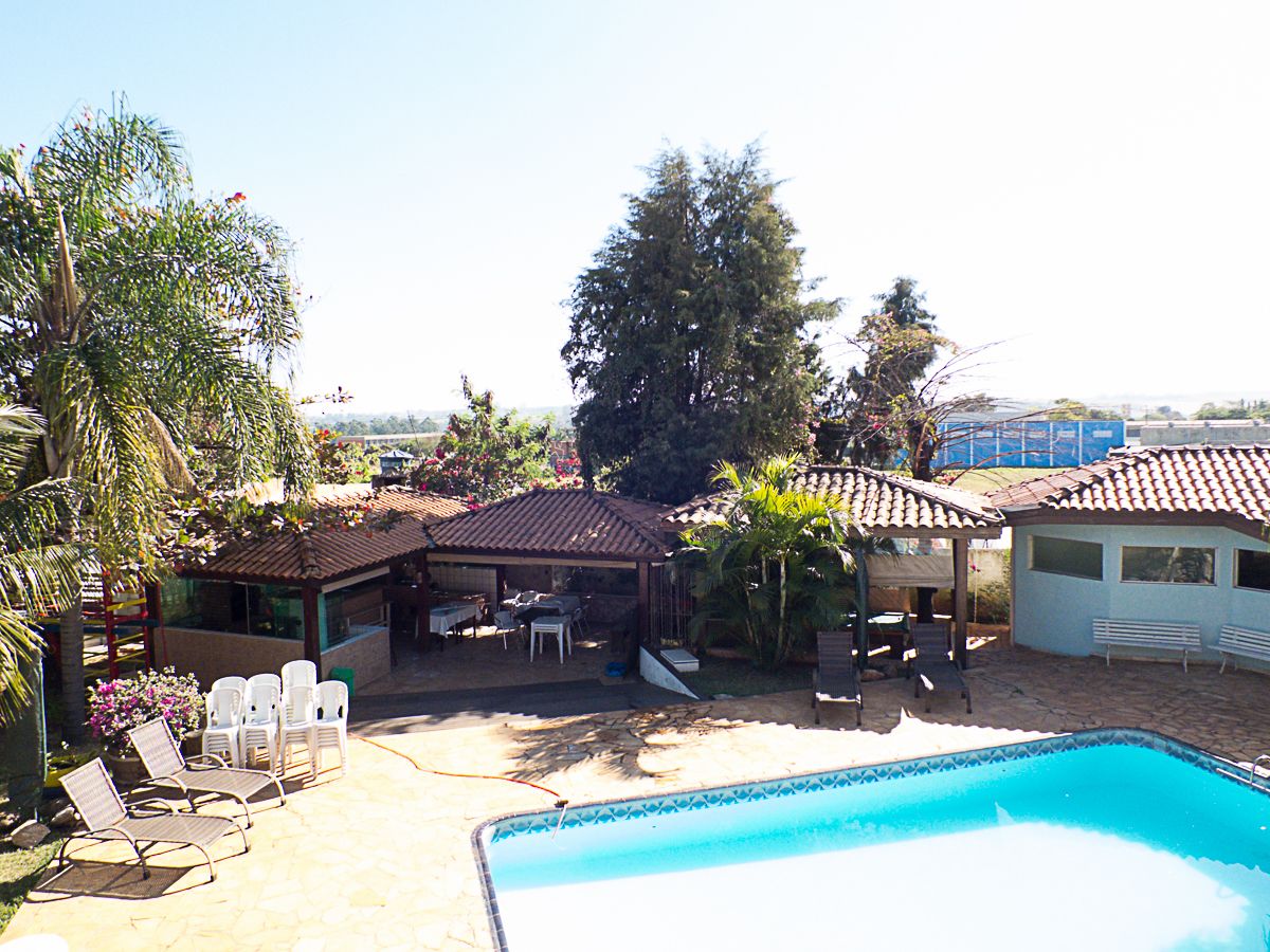 Un patio trasero con piscina, mobiliario de jardín y una zona de estar cubierta.