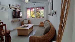 Una sala de estar con sofá, mesa de centro, televisión y ventilador.