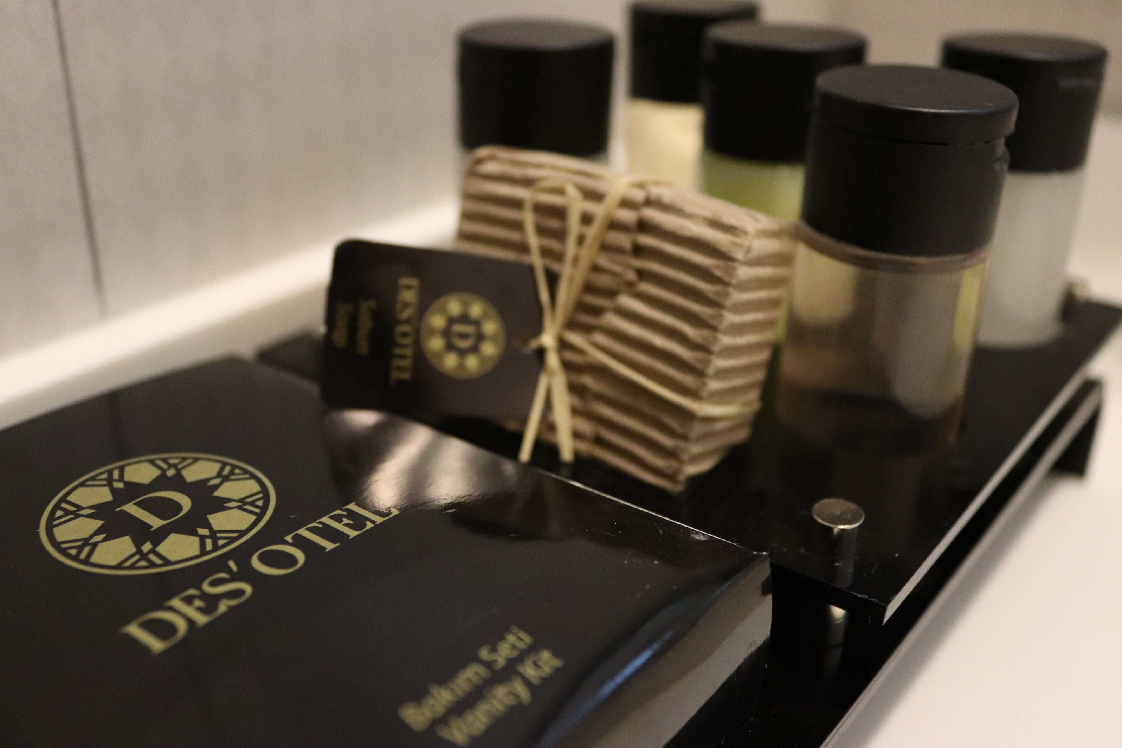 A black tray with a black box labeled 'DES' OTEI' and several black bottles.