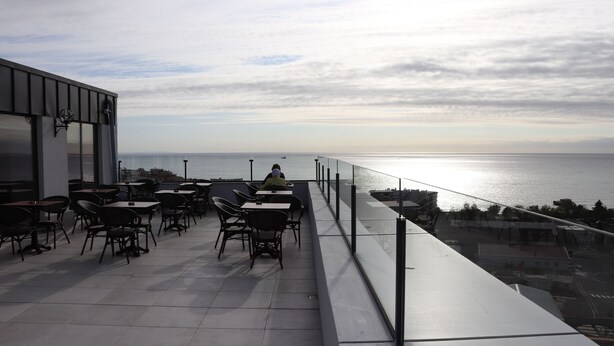 Una terraza con mesas y sillas con vista al mar.