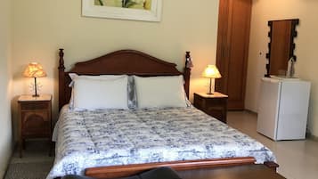 Quarto bem arrumado com uma cama, mesas de cabeceira, um banco, uma geladeira e um espelho.