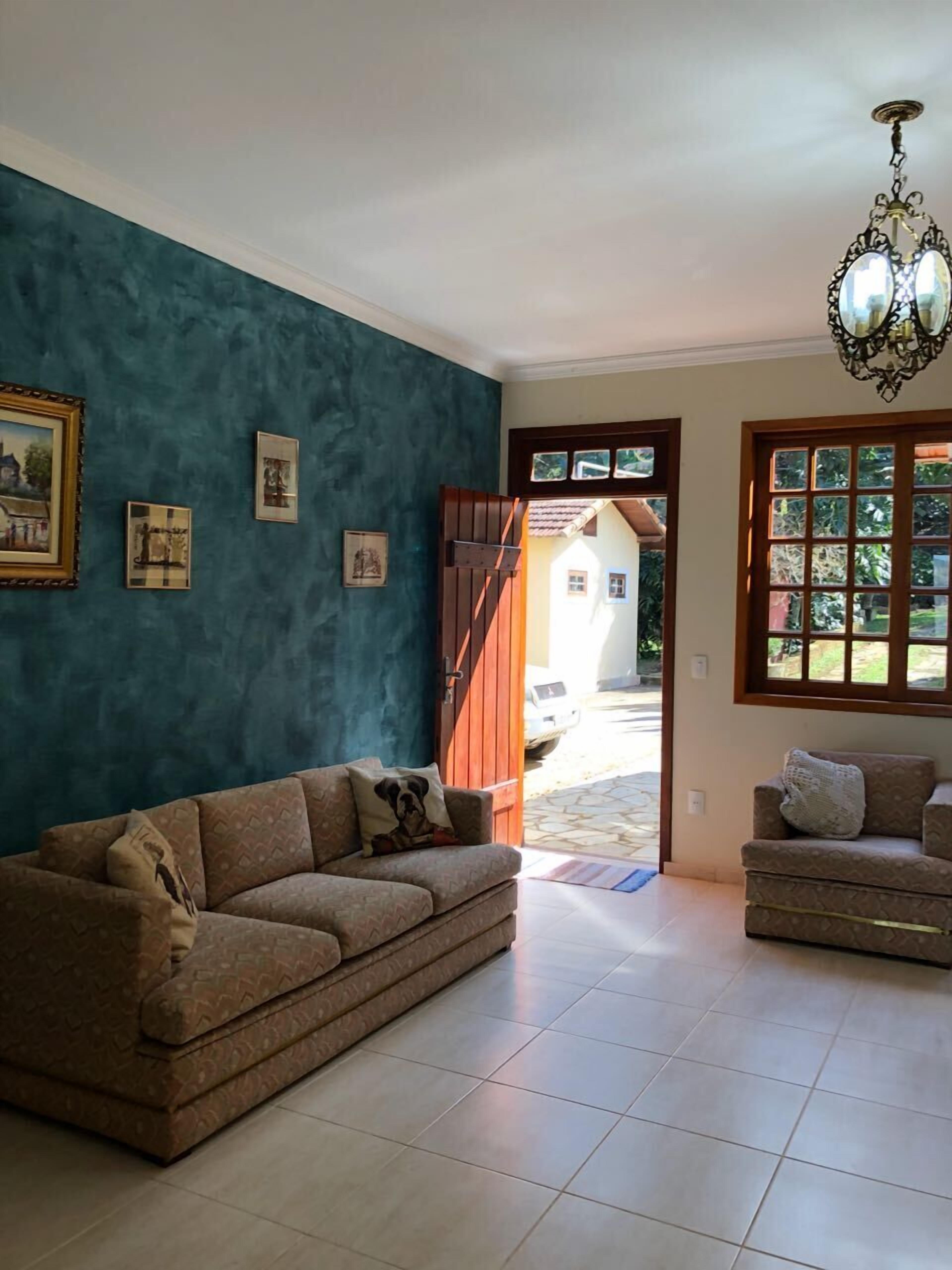 A living room with a blue wall, two sofas, a chandelier, and a door leading outside.