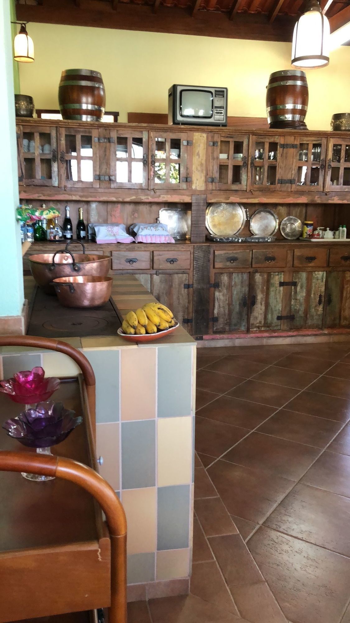 Uma cozinha rústica com armários de madeira, uma televisão e utensílios de cobre.