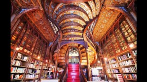 A library with ornate wooden architecture, bookshelves on both sides, and a central staircase. - Maria da Sé Historic House (Porto)