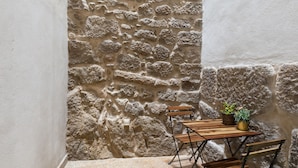 A stone wall with a wooden bench and two potted plants. - Maria da Sé Historic House (Porto)