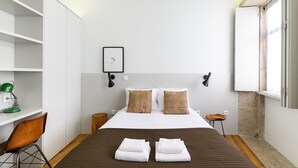 A modern hotel room with a bed, a desk, a chair, and a window. - Maria da Sé Historic House (Porto)