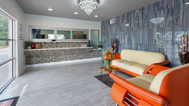 Un salon moderne avec un mur d’accent en pierre, un lustre et un canapé agrémenté de coussins orange.