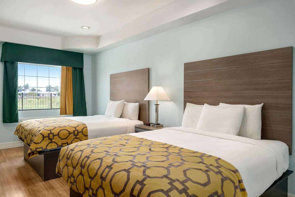 Een hotelkamer met twee bedden, een raam met gordijnen, een lamp en uitzicht op de omgeving.