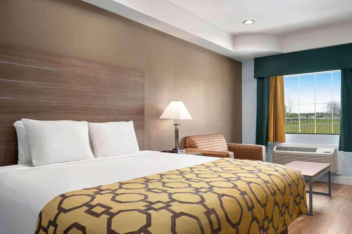 Een hotelkamer met een bed, een stoel, een lamp en een raam met uitzicht.