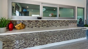 Un espace d’accueil avec un mur recouvert de carreaux, une grande fenêtre et une statue de Bouddha.