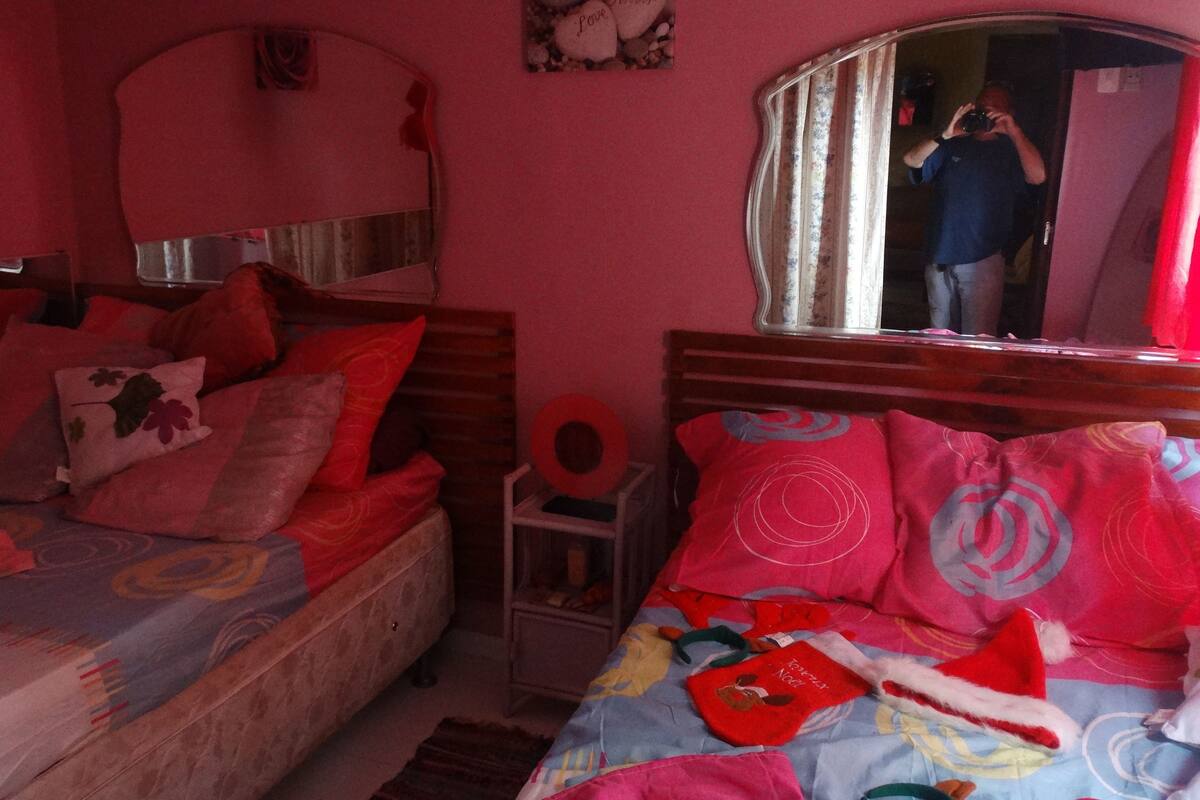A bedroom with two beds, a mirror, and a small bedside table.