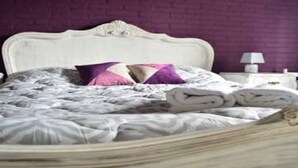 A bed with a white headboard, a purple pillow, and a white lamp on a bedside table. - El Viajero Hostels & Suites - Punta del Este (Punta del Este)