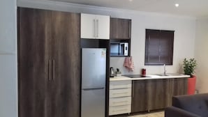 Una cocina compacta equipada con refrigerador, microondas y pileta.
