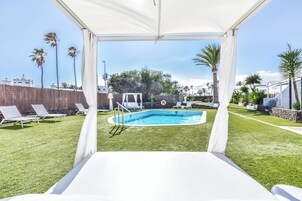 Una piscina al aire libre, sombrillas, sillones reclinables de piscina