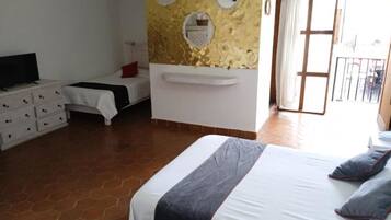 A bedroom with a bed, a dresser, a TV, and a wall with decorative plates.