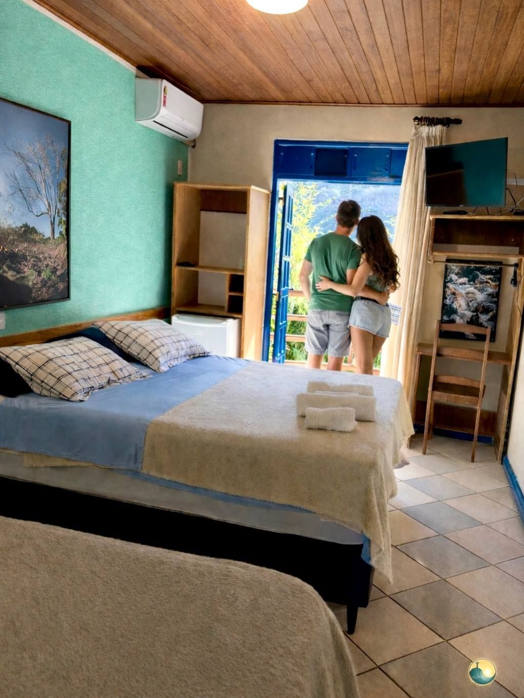 A bedroom with a bed, a desk, a chair, and a television.