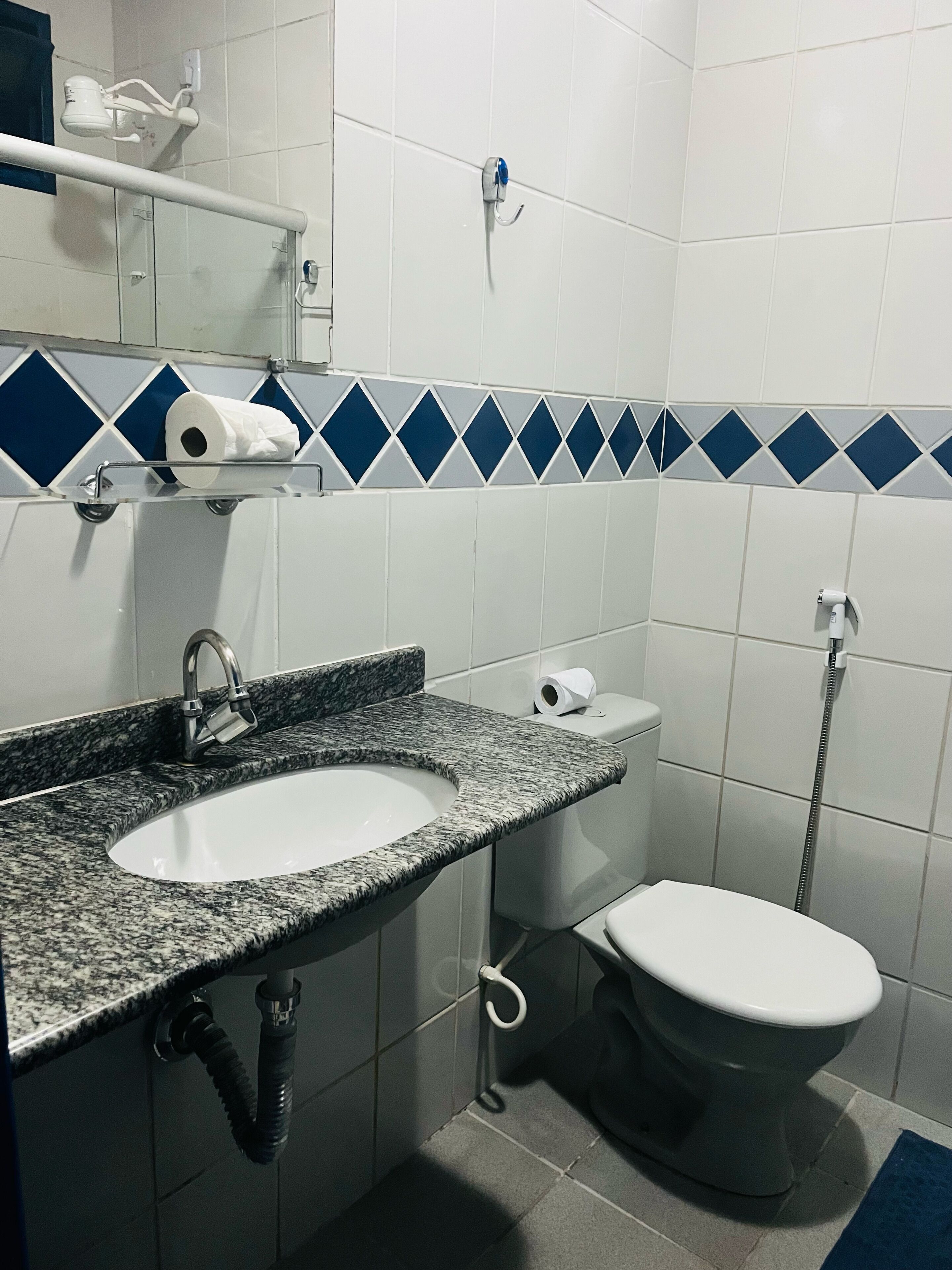 Un baño con lavamanos de granito, inodoro blanco y azulejos azules estampados con diseño de diamantes.