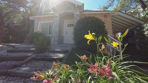 A house with a stone facade, a small porch, and a garden with yellow and pink flowers. - Cabañas Victoria (Mar de Las Pampas)