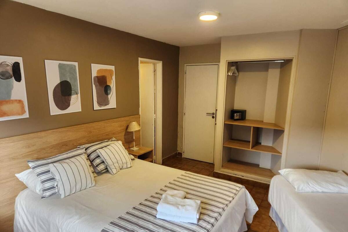 Een hotelkamer met een groot bed, een nachtkastje met lamp, een garderobe en kunst aan de muur.