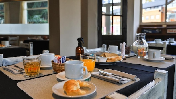 A breakfast setup with a table, breakfast items, and a window view. - Trip Bariloche Select Hostel (San Carlos de Bariloche)