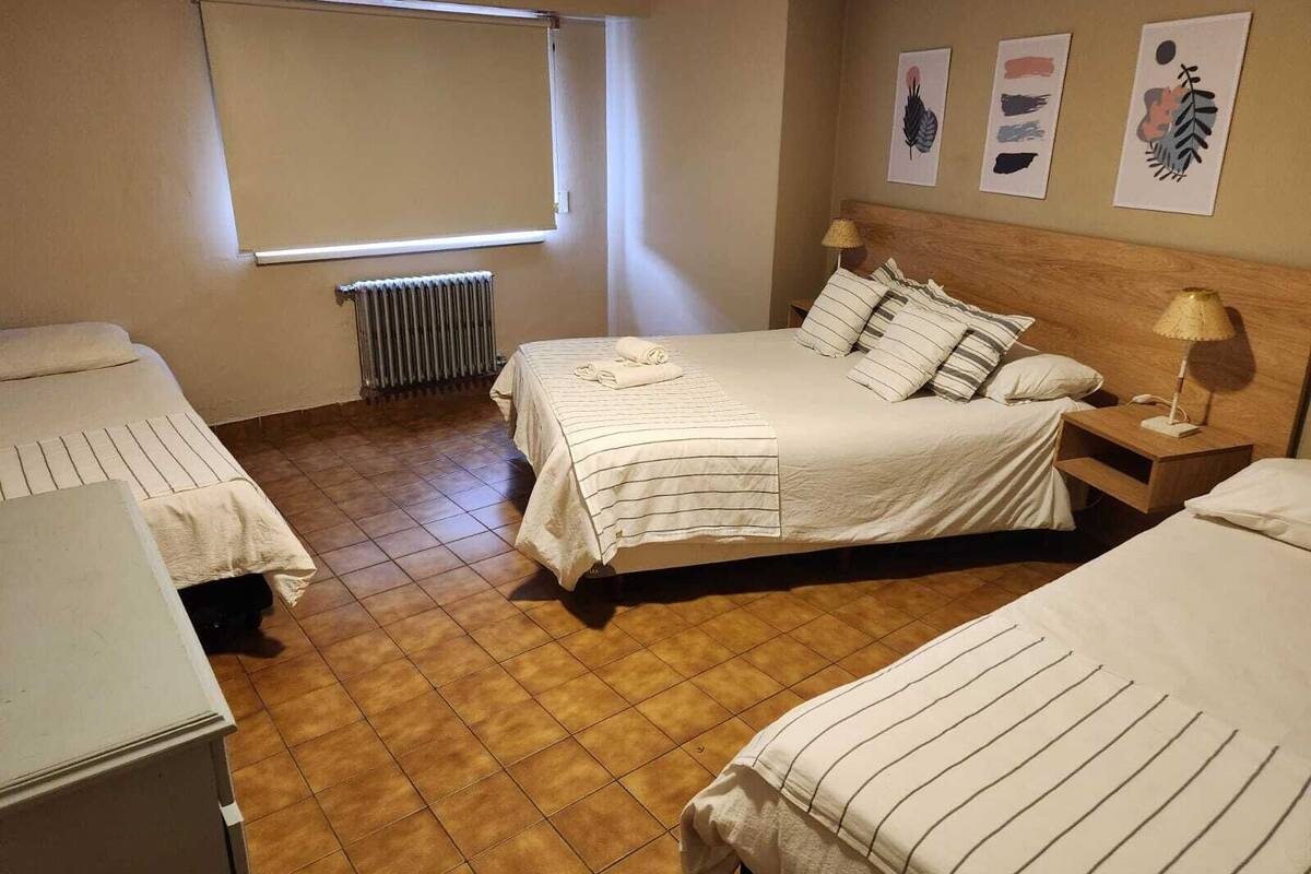 Een hotelkamer met twee bedden, een radiator, een raam en kunst aan de muur.