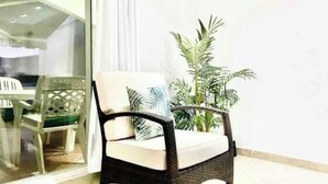 A wicker chair with a cushion and a potted plant beside it. - Villa Marietta (Jolly Harbour)