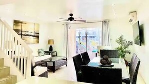 A modern living room with a dining area, a staircase, and a ceiling fan. - Villa Marietta (Jolly Harbour)