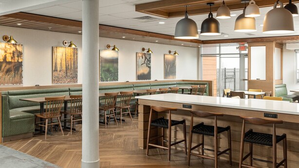 A restaurant with booths, high-top bar stools, and pendant lighting.