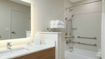 Un baño moderno con un espejo grande, un lavamanos, una ducha con puerta de vidrio y una bañera.